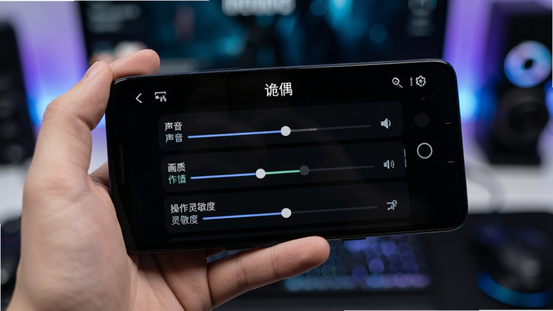 主体为一部安卓手机,屏幕显示《诡偶》游戏设置界面,背景为深色模式,清晰显示“声音”、“画质”、“操作灵敏度”等选项滑块,手机握持在手中,背景虚化,科技风格,清晰细节,无多余文字