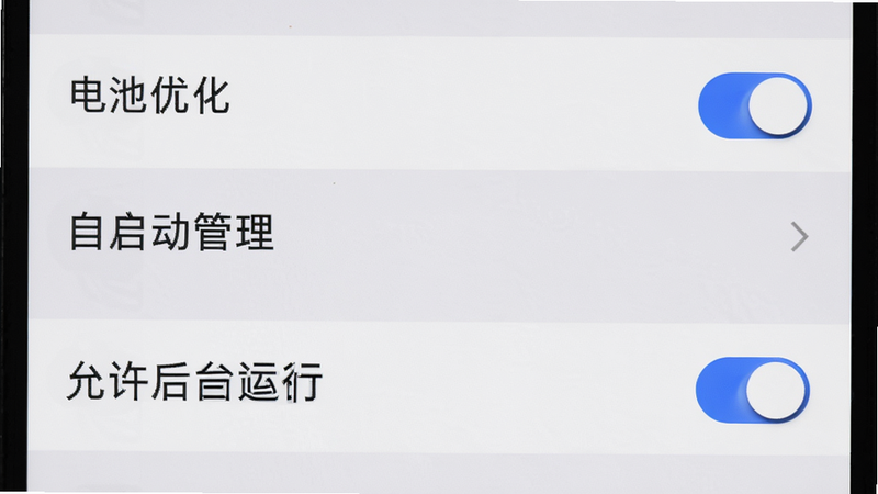 主体为手机设置界面,显示“电池优化”和“自启动管理”选项,布局为列表形式,高亮显示“允许后台运行”开关,排版清晰,风格为系统原生UI,细节包含蓝色开关滑块,画质高清,干净无水印