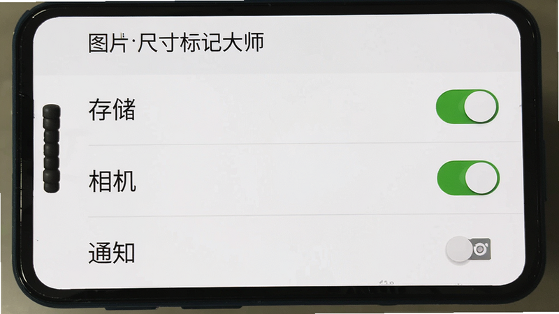 展示手机设置界面,主体为“图片尺寸标记大师”的权限管理页面。布局为垂直列表,清晰显示“存储”、“相机”、“通知”等权限开关,其中“存储”权限呈开启状态,开关为绿色。背景为系统默认的白色设置界面,字体清晰易读。风格为原生Android系统风格,简洁直观,细节真实,高清截图质感。