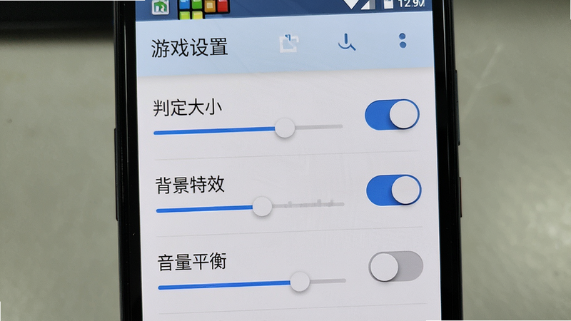 主体为‘节奏方块’在安卓手机上的设置界面,画面聚焦于‘游戏设置’页面,显示‘判定大小’、‘背景特效’、‘音量平衡’等选项,背景为手机屏幕边框,布局为垂直列表式,排版紧凑清晰,风格为真实UI截图风,细节展示开关按钮的滑动状态,画质清晰,无模糊,正面特写,突出设置选项的易用性