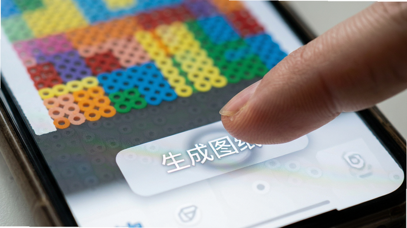 图转拼豆图纸集手机端界面特写,主体为手指点击“生成图纸”按钮的特写,背景虚化显示生成的彩色网格,风格真实摄影风,细节体现触控反馈,画质高清,无杂乱背景
